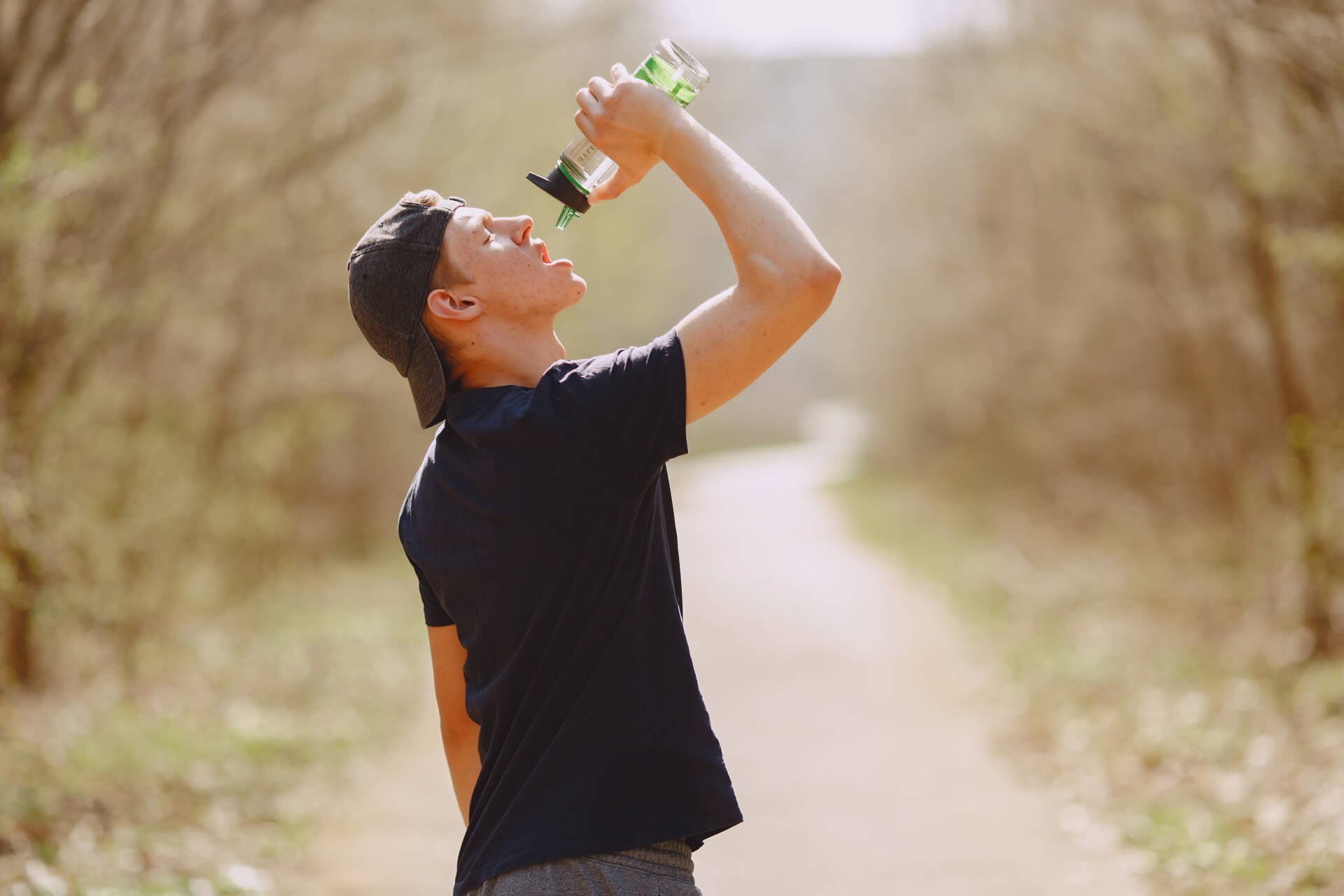 Thirsty man drinking water during training in park