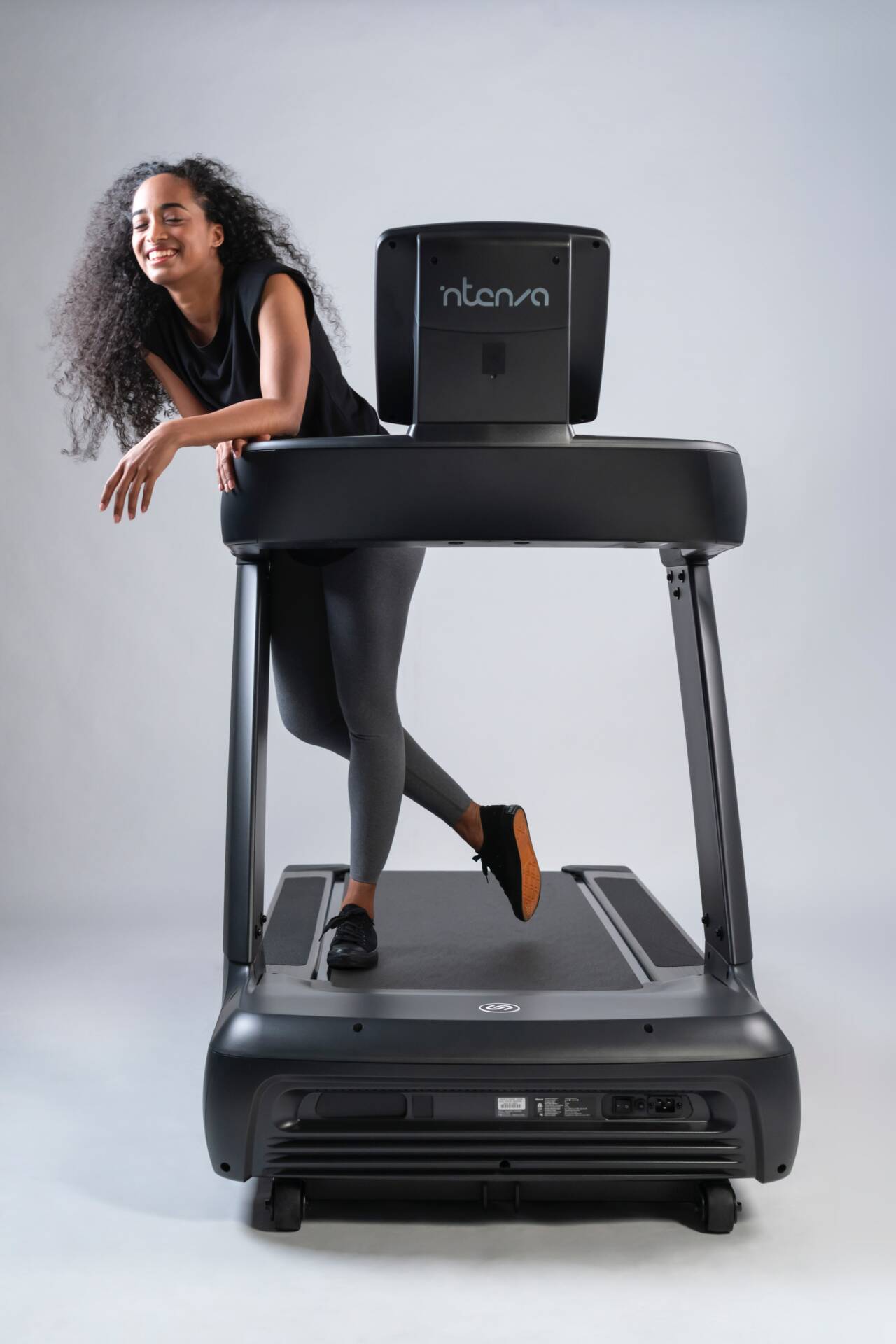 Happy, fit young woman pauses from her workout on an Intenza 450 Series Treadmill to share a smile.