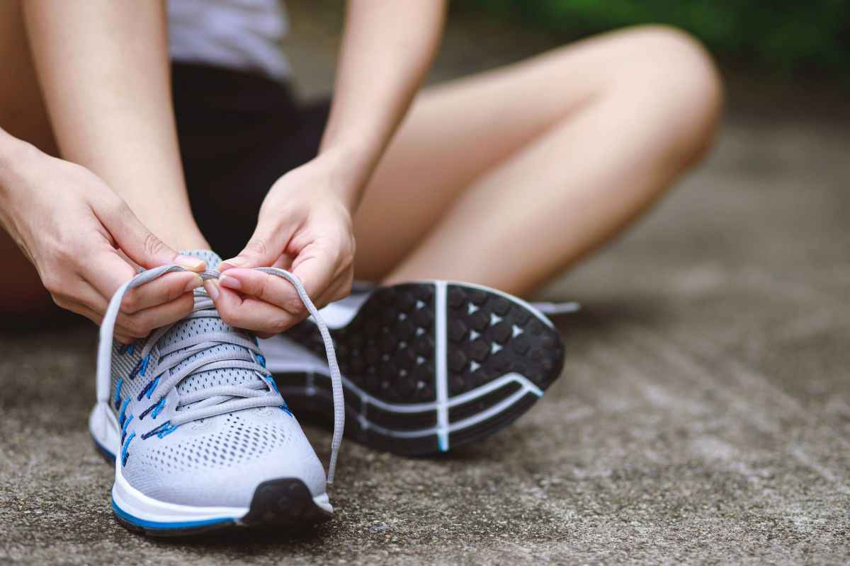 donna che allaccia le scarpe seduta a terra