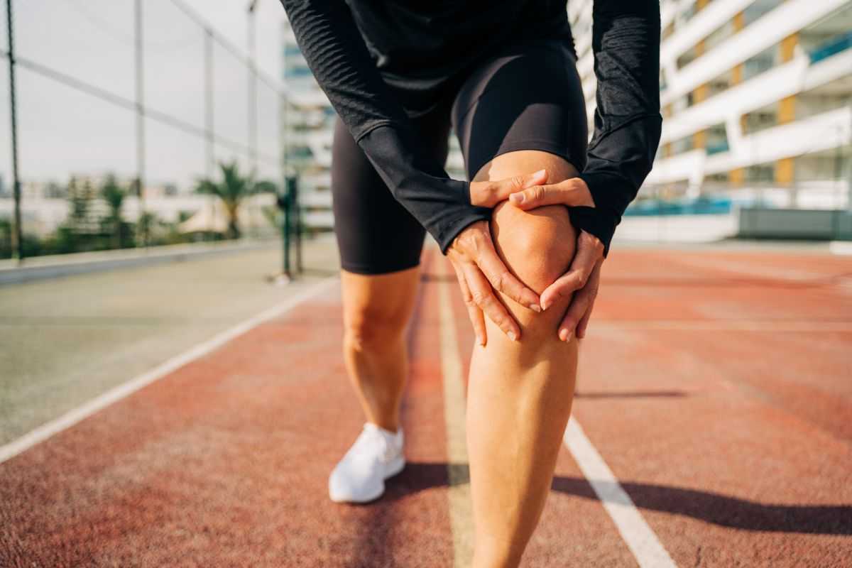 Uomo che si tiene un ginocchio durante una corsa